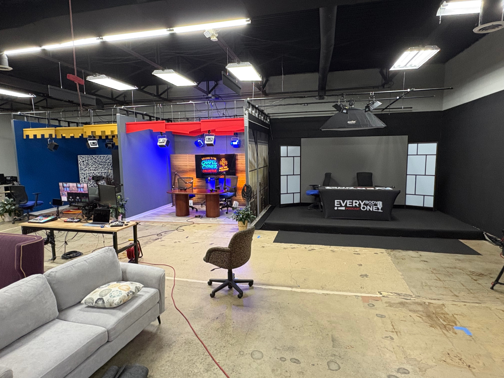 Wide shot of the LiT Podcast Academy studio with podcast sets, production equipment, and seating areas